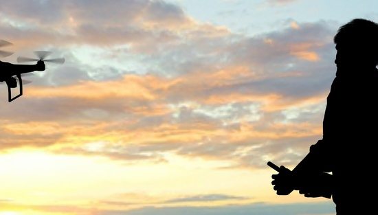 ドローンを操縦する男性と夕日